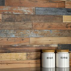 two canisters sitting on top of a wooden table next to each other in front of a wood wall