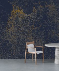 a chair and table in front of a wall with gold paint splattered on it