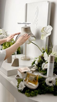 a woman is decorating a table with white flowers and greenery on the side