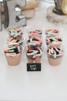 cupcakes with sprinkles are sitting in plastic cups on a table