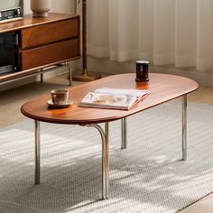 a coffee table with a magazine on it in front of a window and a television