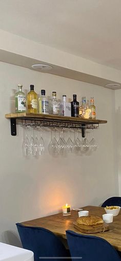 a dining room table with wine glasses and plates on the shelf above it, next to a bar