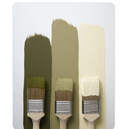 three paintbrushes with different shades of green and white on the wall in front of each other