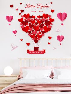 a bed with pink sheets and pillows in front of a wall that has hearts on it