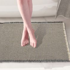 a person standing on a rug in front of a bath tub