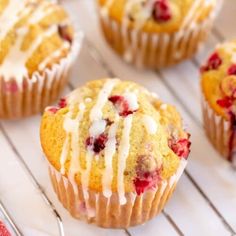 muffins with icing and strawberries sitting on a cooling rack