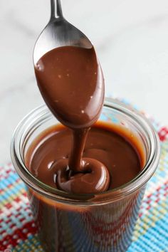 a spoon full of melted chocolate on top of a jar