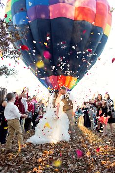 a bride and groom are surrounded by confetti as balloons fly in the sky