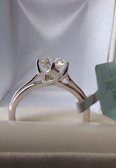 an engagement ring with a heart shaped diamond on it sitting in a white velvet box