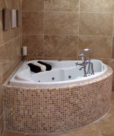 a bathtub in the corner of a tiled bathroom