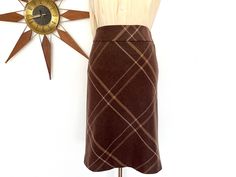 "Vintage 1990s brown and tan plaid wool blend A line skirt by Ann Taylor. This classic wool skirt is a pretty shade of chocolate brown and tan in a wide plaid pattern. It zips up the side with a hook and eye at the top and is fully lined in a matching brown acetate fabric. This skirt would be perfect for fall with knee high boots! Please note this listing is for the skirt only. Click here to see the sheer butter yellow crepe blouse: https://www.etsy.com/listing/1548874555 Measurements (taken lying flat then doubled where appropriate): Waist: 29\" Hips: 38\" Length: about 23\"  Estimated size: medium; tag says size 4 Measurements of the dress form are 34\", 26\", 35.5\". This skirt was pinned onto the dress form; it is shown unpinned in the seventh photo.  Please be sure to check your measu Crepe Blouse, Tan Plaid, Butter Yellow, Wool Skirt, Cozy Chic, Line Skirt, Wool Skirts, Dress Form, Knee Length Skirt