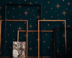 three frames against a blue wall with gold stars on it and one has a marble slab in the middle