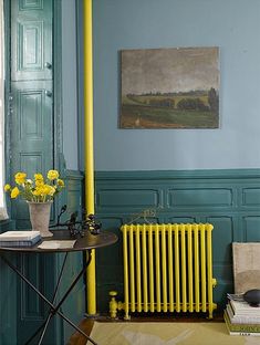 a yellow radiator in the corner of a room with books and vases