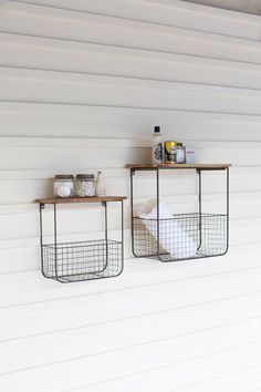 two metal baskets are hanging on the side of a white wall next to each other