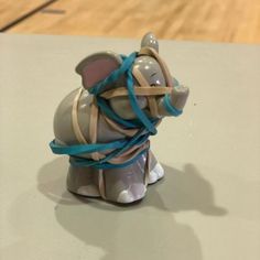 an elephant figurine wrapped in blue ribbon on top of a wooden floor next to a basketball court