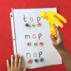 a child's hand holding a yellow plastic object over a map with letters and numbers on it