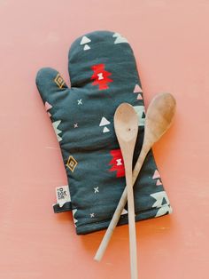 a pair of oven mitts and a wooden spoon on a pink surface