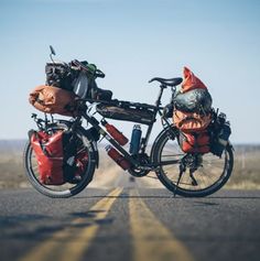 two bikes with bags strapped to the back parked on the side of the road in the middle of nowhere