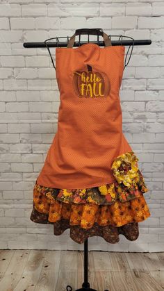 an orange apron with the words hello fall on it, sitting on top of a mannequin