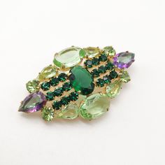 Outstanding glass rhinestone vintage brooch featuring emerald green, grass green, and watermelon open-back stones! Made in Czechoslovakia in the 1960s, it has a beautiful golden color finish. It's in excellent condition, with a perfectly working closure. The brooch is not signed.  Dimensions: 1 1/4" by 2 1/2". Antique Green Gemstone Brooches, Mid-century Green Brooch For Formal Occasions, Mid-century Green Brooches For Formal Occasions, Green Oval Brooches For Formal Occasions, Green Mid-century Style Brooches For Formal Occasions, Mid-century Green Formal Brooches, Retro Green Brooch Jewelry, Art Deco Green Brooches For Wedding, Green Art Deco Brooches For Wedding