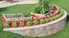 a garden in the middle of a yard with flowers and plants growing on top of it