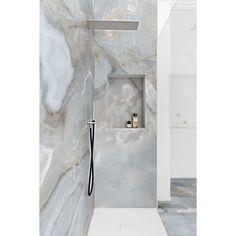 a bathroom with marble walls and flooring, including an open shower head in the corner