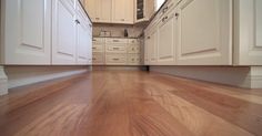 an empty kitchen with white cabinets and wood floors