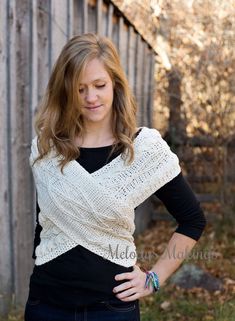 a woman standing in front of a fence wearing a knitted shawl and black shirt