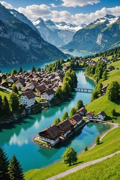 an aerial view of a small village in the middle of a valley with water and mountains behind it