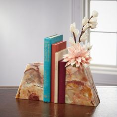 two books are stacked on top of each other with flowers in the middle and one is pink