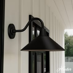 an outdoor wall light on the side of a house with white siding and black trim