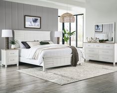 a white bed sitting on top of a wooden floor next to a dresser and mirror