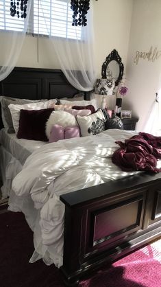 a bed with purple and white pillows in a bedroom next to a pink area rug