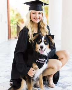 a woman sitting on the ground with her dog wearing a graduation cap and gown in front of her