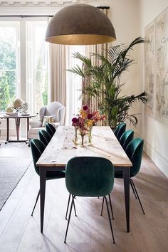 a dining room table with green chairs and a large potted plant in the center