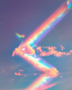 an airplane flying in the sky with a rainbow colored tail