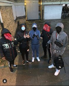 four people wearing masks standing on the sidewalk