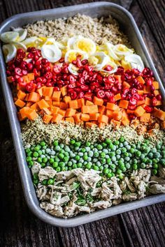 a tray filled with rice, peas, carrots and hard boiled eggs on top of it