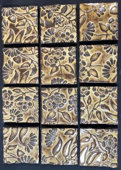 four square tiles with gold and black designs on them, one is made out of wood