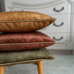 three pillows stacked on top of each other in front of a dresser with drawers and drawers