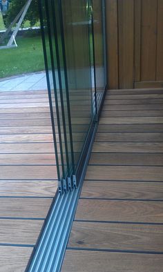 a cat is sitting on the wooden floor next to a glass door and looking at its reflection