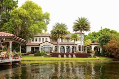 a large house sitting on top of a lush green field next to a body of water