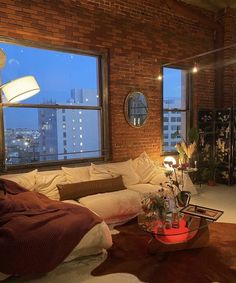 a living room filled with furniture and lots of windows next to a tall building at night