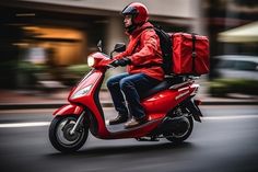 a man riding on the back of a red scooter down a city street