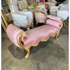 a pink and gold chaise lounge with matching cushions in a room filled with furniture