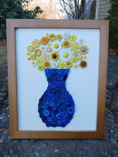 a blue vase with yellow and white flowers in it sitting on top of a rock