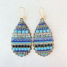 "Dive into these dramatic teardrop statement earrings in exotic sea-inspired blue tones. Perfect rows of stunning Swarovski rhinestones and glass beads mounted on tear-drop metal filigree stampings in an antique bronze finish create a perfect blue-tone statement earring to add a pop of color. Lightweight. 3\"L x 1.25\"W. Gold-plated, nickel-free ear wires. Handmade in USA." Bohemian Jeweled Beaded Drop Earrings, Blue Metal Earrings With Rhinestones, Blue Jeweled Metal Earrings, Bohemian Blue Jeweled Earrings, Blue Beaded Teardrop Chandelier Earrings, Blue Bohemian Crystal Earrings, Blue Jeweled Teardrop Earrings, Bohemian Blue Crystal Earrings, Blue Teardrop Bohemian Chandelier Earrings