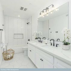 a white bathroom with two sinks and a large mirror on the wall over the bathtub