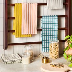 towels hanging on the wall next to a cutting board with utensils and other kitchen items