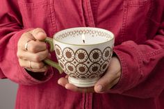 a person holding a coffee cup with a candle in it's hand and wearing a red shirt